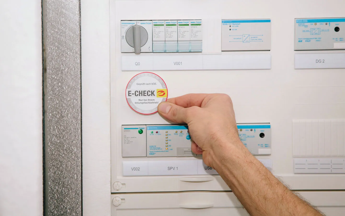 E-CHECK - Mitarbeiter klebt in der Verteilung die E-CHECK Plakette an &middot; W.S. Elektro