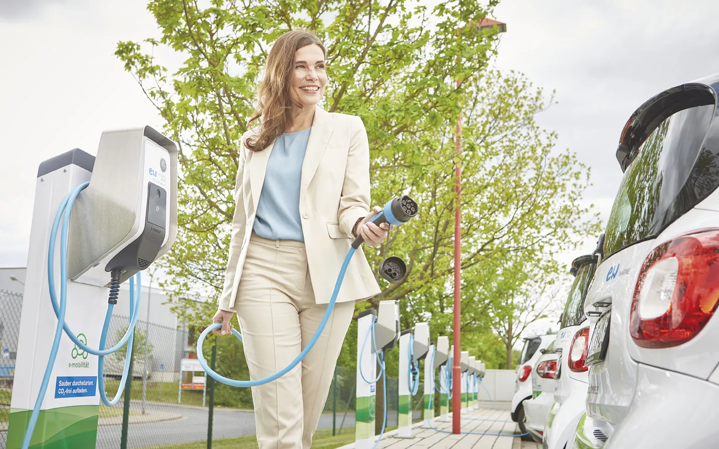 E-Mobilität - Kundin vor Ladestation mit Stecker in der Hand &middot; W.S. Elektro